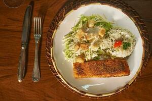 schön Teller von gegrillt Fisch mit Reis. im das Hintergrund alt Bücher foto