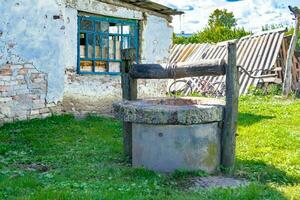 alter Brunnen mit Eiseneimer an langer geschmiedeter Kette für sauberes Trinkwasser foto