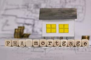 Abkürzung fha Hypothek zusammengesetzt von hölzern Briefe. klein Papier Haus im das Hintergrund. foto