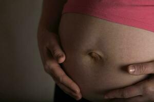 jung schwanger Frau berührt ihr Bauch. dramatisch Licht. foto
