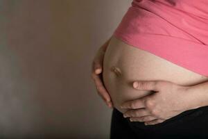 jung schwanger Frau berührt ihr Bauch. dramatisch Licht. foto