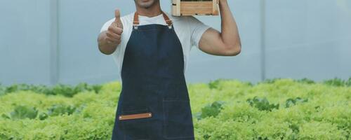 jung asiatisch Frau und Senior Mann Farmer Arbeiten zusammen im organisch hydroponisch Salat Gemüse Bauernhof. modern Gemüse Garten Inhaber mit Digital Tablette prüfen Qualität von Grüner Salat im Gewächshaus Garten. foto