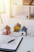 Haus Modell- mit echt Nachlass Agent und Kunde diskutieren zum Vertrag zu Kaufen Haus, Versicherung oder Darlehen echt Immobilien, real Nachlass Konzept. foto
