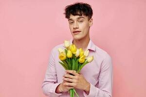 ziemlich Mann im ein Rosa Hemd mit ein Strauß von Blumen gestikulieren mit seine Hände Modell- Studio foto