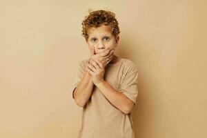 Junge im ein Beige T-Shirt mit lockig Haar posieren foto