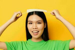 charmant jung asiatisch Frau mit ein medizinisch Maske im Hand Schutz Gelb Hintergrund unverändert foto