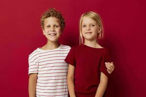 klein Kinder gut Stimmung Stehen Nächster zu posieren rot Hintergrund foto