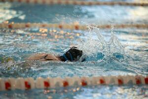 Kind Athlet schwimmt im das Schwimmbad. Schwimmen Abschnitt. foto