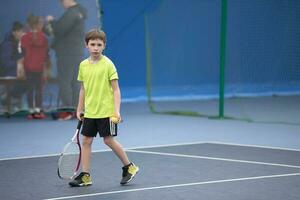 wenig Junge mit ein Tennis Schläger. das Kind Theaterstücke Tennis. foto