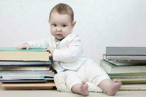 wenig Kind unter Bücher. glücklich sechs Monat alt Baby Junge im ein Stapel von Bücher. das Konzept von früh Kindheit Bildung. foto