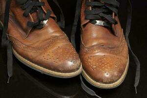 ein Paar von braun Jahrgang Leder Schuhe auf ein dunkel Hintergrund. schön Leder Schuhe. foto