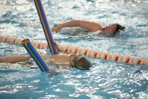 Kind Athlet schwimmt im das Schwimmbad. Schwimmen Abschnitt. foto