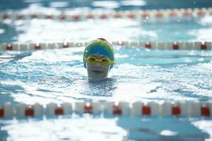 Kind Athlet schwimmt im das Schwimmbad. Schwimmen Abschnitt. foto