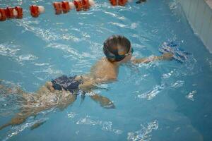 Junge im ein Schwimmen Deckel und Schwimmen Brille im das Schwimmbad. das Kind ist beschäftigt, verlobt im das Schwimmen Abschnitt. foto