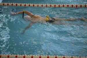 Kind Athlet schwimmt im das Schwimmbad. Schwimmen Abschnitt. foto