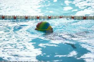 Kind Athlet schwimmt im das Schwimmbad. Schwimmen Abschnitt. foto