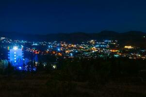 Nacht Landschaft. Aussicht von das Nacht Stadt im ein hügelig Bereich. klein Stadt, Dorf foto
