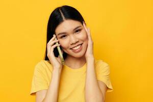 charmant jung asiatisch Frau reden auf das Telefon posieren Technologie Gelb Hintergrund unverändert foto
