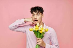 Porträt von ein jung Mann Strauß von Gelb Blumen Romantik posieren Mode Rosa Hintergrund unverändert foto