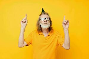 Porträt Alten Mann im ein Gelb T-Shirt mit ein Deckel auf seine Kopf Spaß abgeschnitten Aussicht foto