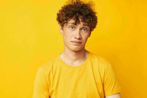 Porträt von ein jung lockig Mann Jugend Stil Brille Studio beiläufig tragen Gelb Hintergrund unverändert foto