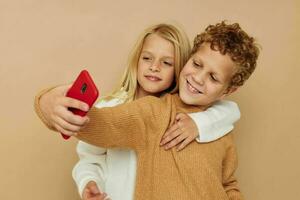 wenig Junge und Mädchen mit ein rot Telefon zusammen Technologien isoliert Hintergrund foto