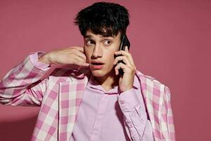 Porträt von ein jung Mann mit ein Telefon im Hand Rosa Blazer Mode elegant Stil Lebensstil unverändert foto