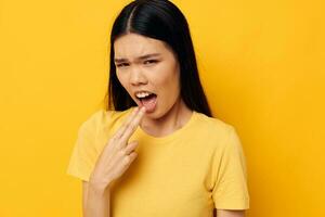 Frau im ein Gelb T-Shirt halten seine Kopf Unzufriedenheit Studio Modell- unverändert foto