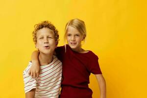 Bild von positiv Junge und Mädchen Stehen Seite durch Seite posieren Kindheit Emotionen Gelb Hintergrund foto
