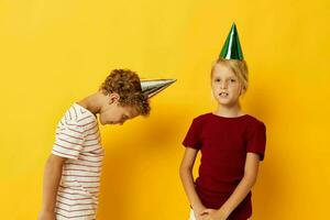 süß Vorschule Kinder Urlaub Spaß mit Kappen auf Ihre Kopf Gelb Hintergrund foto