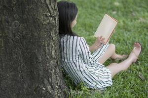 attraktive Frau, die ein Buch im Park liest foto