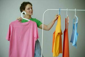 heiter Frau Grün T-Shirts in der Nähe von Kleider Kleiderbügel abgeschnitten Aussicht unverändert foto