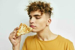 attraktiv Mann im ein Gelb T-Shirt Essen Pizza Lebensstil unverändert foto