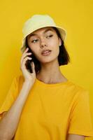schön Mädchen Gelb T-Shirt und Hut Sommer- Stil mit Telefon Lebensstil unverändert foto