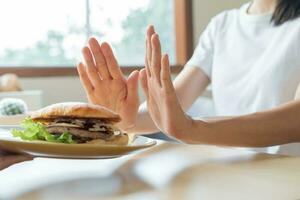 schönheit schlank weiblicher körper verwirren hamburger. frau im restaurant erreicht gewichtsverlustziel für ein gesundes leben, verrückt nach dünnheit, dünner taille, ernährungsberaterin. Ernährung, Körperform. foto