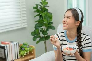 gesund Lebensmittel. schön weiblich Mädchen genießen Essen Joghurt, Granola, frisch Früchte auf Frühstück Gesundheit im Haus. glücklich jung Frau Lächeln auf Morgen gut Emotion. Diät, Entgiftung, Diät, sauber essen, Vegetarier foto