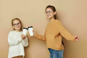 zwei wenig Mädchen Einweg Brille posieren Beige Hintergrund foto