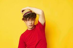 jung lockiges Haar Mann im ein rot T-Shirt mit ein Mode Hut Lebensstil unverändert foto