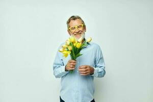 Porträt von glücklich Senior Mann ein Strauß von Blumen mit Brille wie ein Geschenk Licht Hintergrund foto