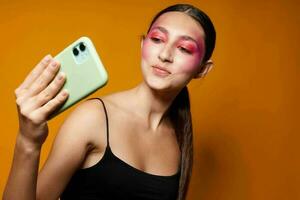 sexy Brünette Frau sieht aus beim das Telefon hell bilden posieren Mode Emotionen isoliert Hintergrund unverändert foto