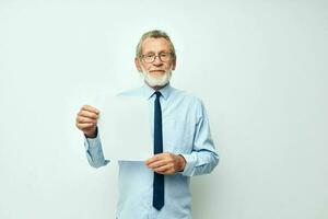 Senior grauhaarig Mann im ein Hemd mit ein Krawatte Kopierraum Blatt von Papier isoliert Hintergrund foto