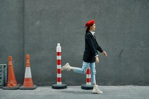 Mode Frau Laufen Nieder das Straße im Vorderseite von das Stadt Tourist im stilvoll Kleider mit rot Lippen und rot Baskenmütze, reisen, filmisch Farbe, retro Jahrgang Stil, spät zu arbeiten, laufen. foto