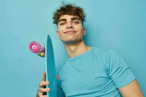 gut aussehend jung Mann Blau Skateboard im Hand isoliert Hintergrund foto