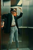 stilvoll Frau im schwarz Jacke und Sonnenbrille posieren im Aufzug, Mode Modell- foto
