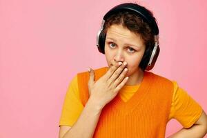 Porträt von ein jung Frau Grimasse Kopfhörer Unterhaltung Emotionen Musik- Rosa Hintergrund unverändert foto