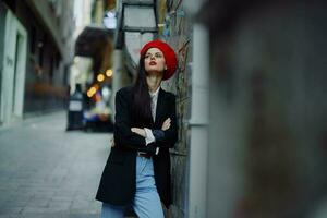 Mode Frau Porträt Gehen Tourist im stilvoll Kleider mit rot Lippen Gehen Nieder eng Stadt Straße, reisen, filmisch Farbe, retro Jahrgang Stil, dramatisch. foto