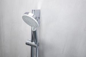 Duschkopf auf einer grauen Mikrozementwand eines modernen Badezimmers foto