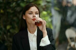 Frau mit rot Lippen Lächeln mit Zähne Trinken Tee im ein Cafe von ein Türkisch Glas Becher auf das Straße, Sommer- reisen, Ferien im das Stadt foto