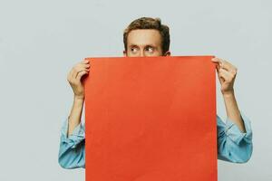 Porträt von ein Erwachsene männlich auf ein grau Hintergrund mit ein rot Stück von Papier zum Ihre Design und Text, Layout, Kopieren Raum, Raum zum Text foto