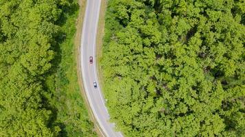 Luft Draufsicht Auto, das durch den Wald auf Landstraße fährt foto